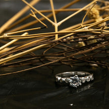 Load image into Gallery viewer, Silver ring with a diamond on a dark surface with dry grass
